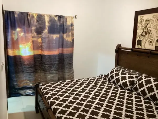 Bedroom with an Ocean Front Lavish *Jr Penthouse* Exquisite Views covered in a giraffe print blanket and a sunset-themed curtain hanging on the window.