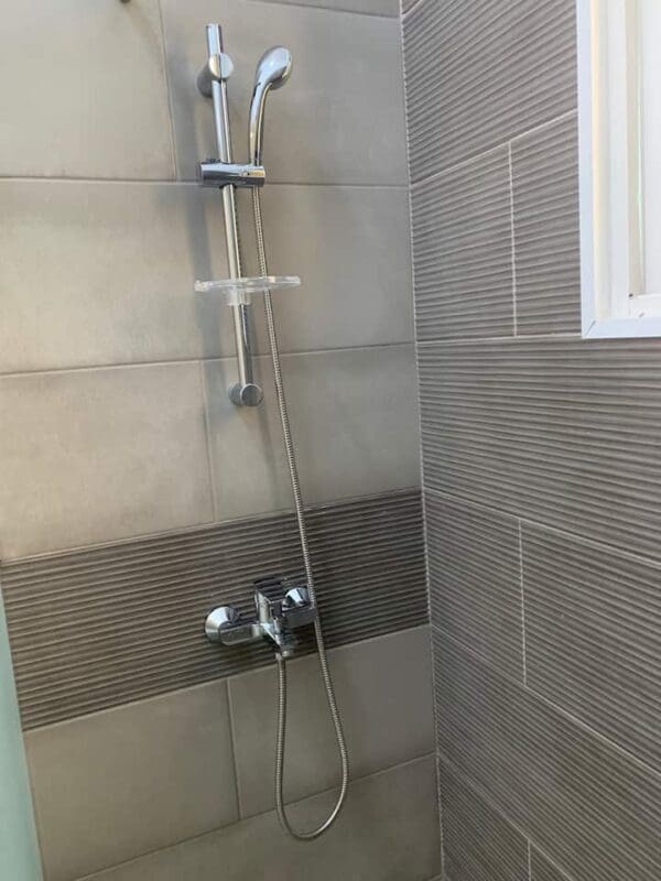 A shower with a tiled wall and floor