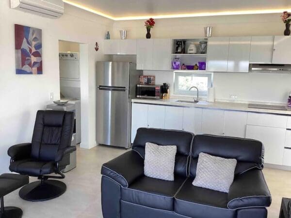 A living room with black leather furniture and white walls.