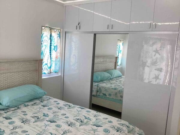 A bedroom with white walls and blue sheets.