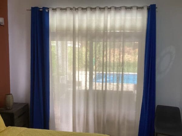 A bedroom with a pool in the background.