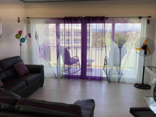 A living room with purple curtains and black furniture.