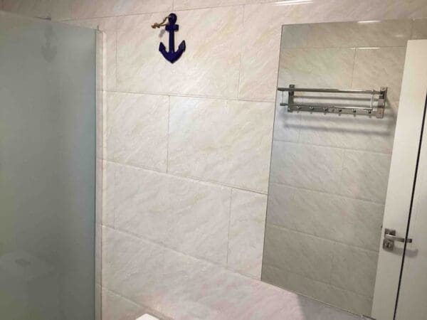 A bathroom with white tile and a blue anchor on the wall.