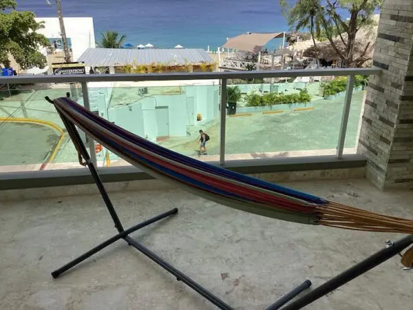 A colorful hammock on a balcony overlooking the Ocean Front Lavish *Jr Penthouse* Exquisite Views with a swimming pool and ocean in the background.