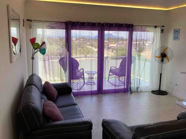 A living room with purple curtains and a view of the water.