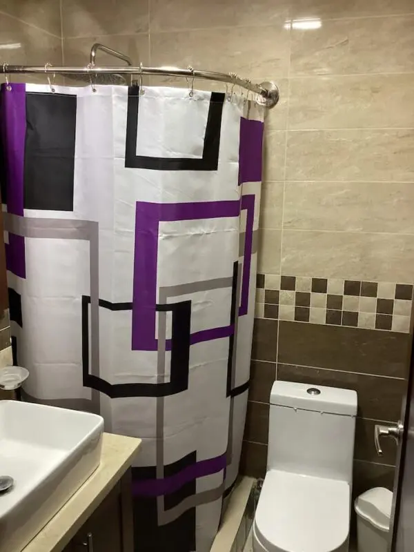 A modern bathroom featuring a Ocean Front Lavish *Jr Penthouse* Exquisite Views shower curtain in shades of purple, black, and white, with a toilet and sink visible.