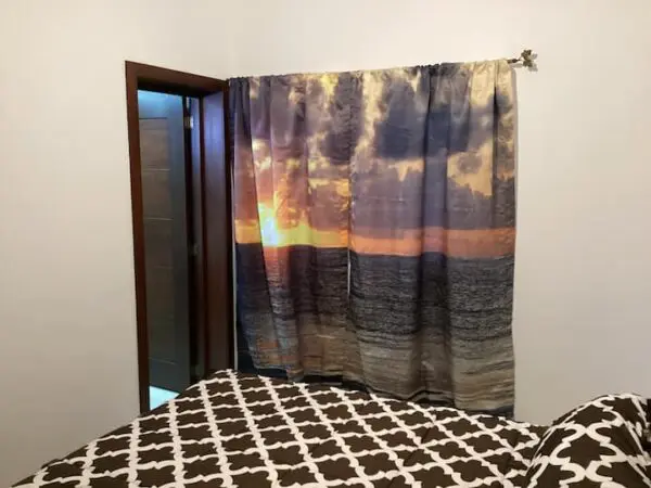 A bedroom with an Ocean Front Lavish *Jr Penthouse* Exquisite Views covering a doorway, and a bed with a brown and white patterned comforter in the foreground.