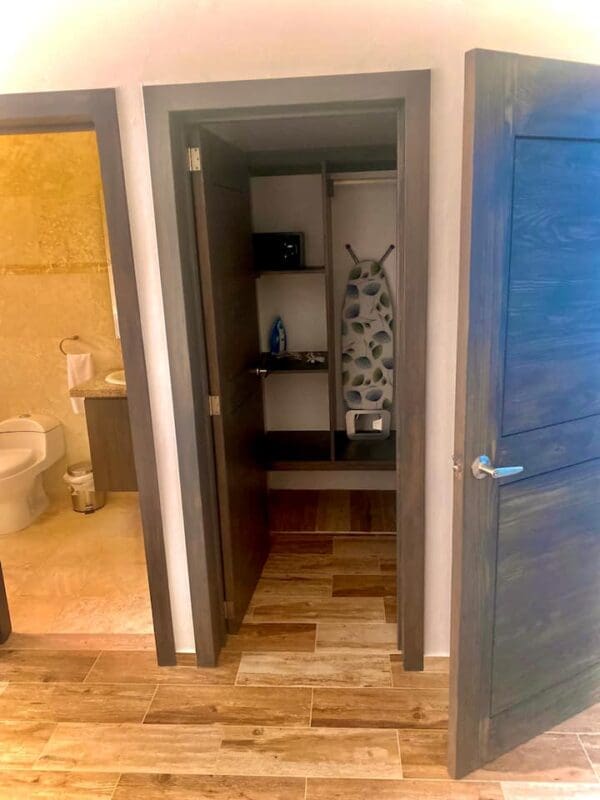 A giraffe is standing in the doorway of a bathroom.