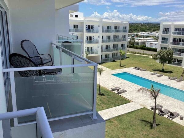 A balcony with chairs and pool in the background.