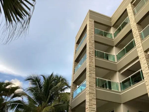 Ocean Front Lavish Jr Penthouse Exquisite Views apartment building with balconies under a cloudy sky, flanked by palm trees.