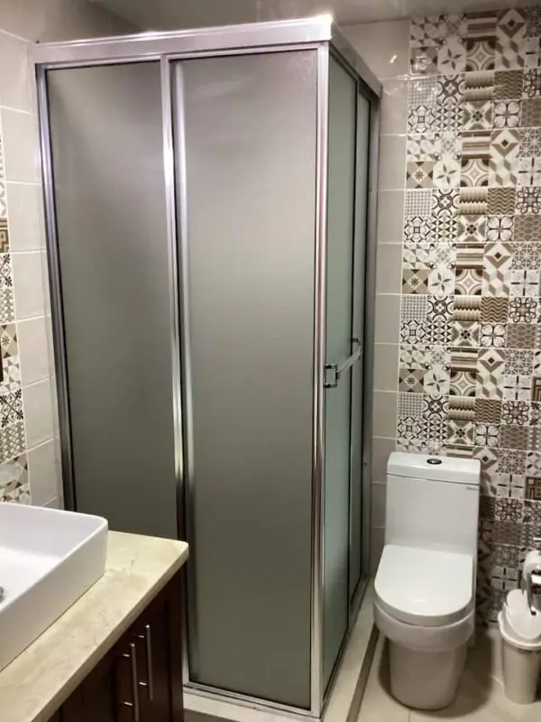 A modern bathroom with a frosted glass shower enclosure next to a white toilet, with patterned tiles on the walls in the Ocean Front Lavish *Jr Penthouse* Exquisite Views.