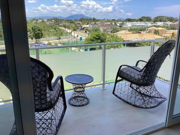 A balcony with two rocking chairs and a table.