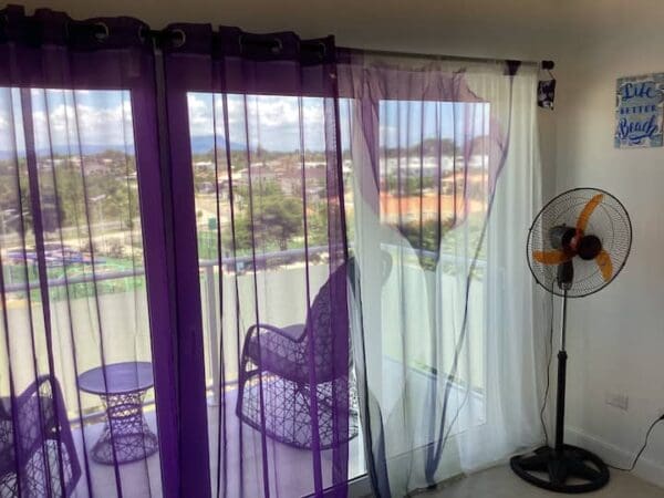 A purple chair and fan in front of the window.