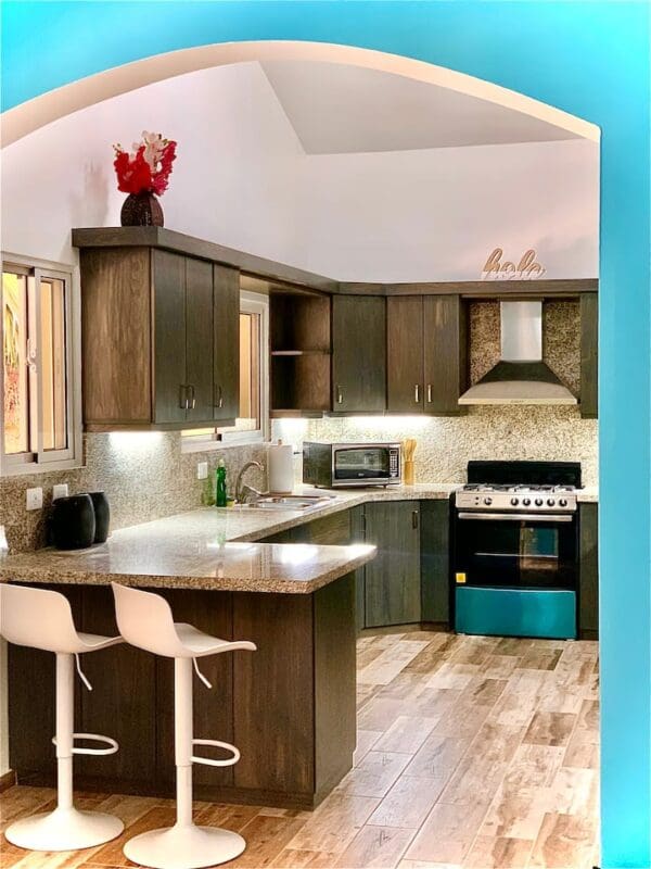 A kitchen with wooden floors and white chairs.