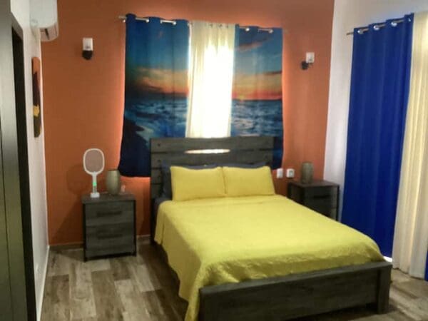 A bedroom with an orange wall and yellow bed spread.