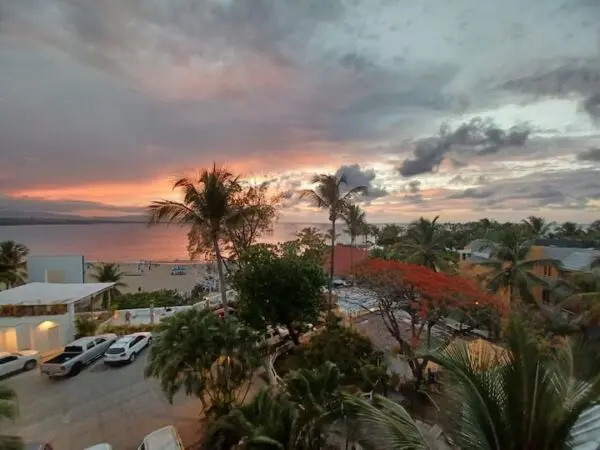 Ocean Front Lavish *Jr Penthouse* Exquisite Views view over a beachfront with palm trees and a colorful sky, seen from a balcony.