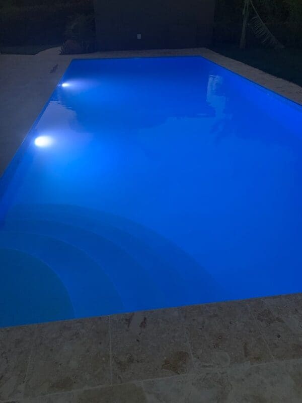 A pool with blue water and lights on it.