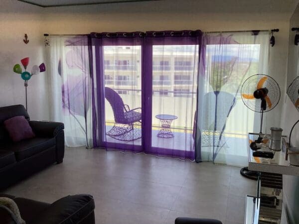 A living room with purple curtains and black furniture.