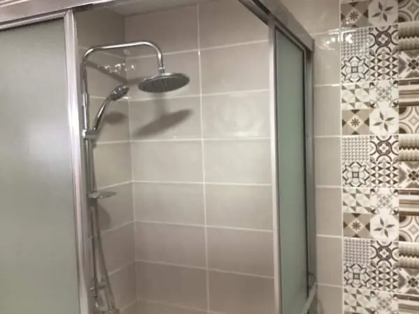 A modern bathroom featuring an Ocean Front Lavish Jr Penthouse Exquisite Views with a large rain shower head and decorative patterned tiles on the adjacent wall.