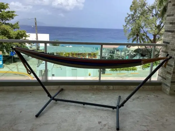 A portable hammock on a balcony overlooking the Ocean Front Lavish *Jr Penthouse* Exquisite Views with palm trees and the ocean visible in the background.