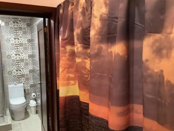 Interior of a small bathroom with a Ocean Front Lavish *Jr Penthouse* Exquisite Views featuring a sunset design, visible toilet and patterned shower tiles.