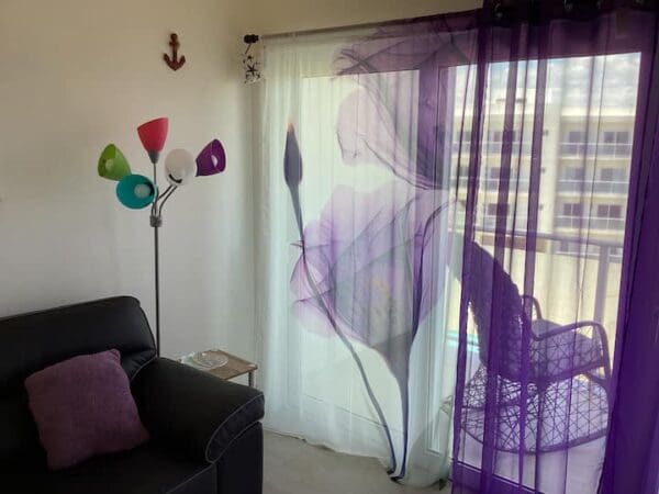 A living room with purple curtains and a black couch